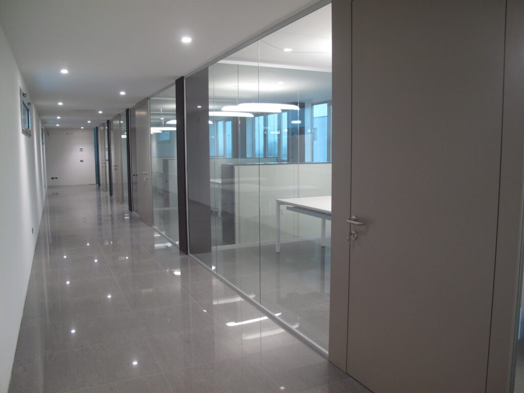 Corridoio uffici con pareti in vetro e finiture eleganti – Povelato